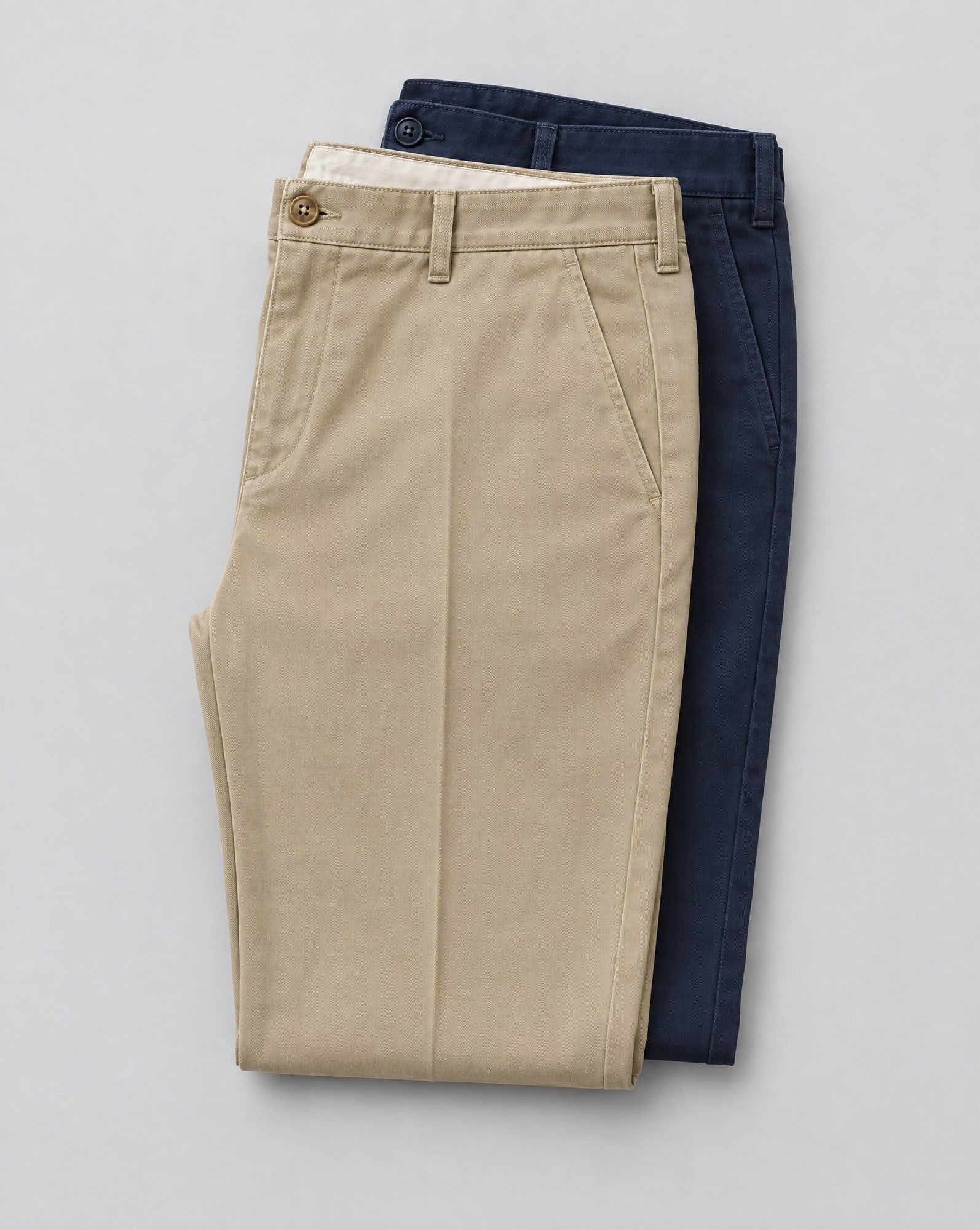 Khaki and navy cotton twill chino trousers folded and stacked