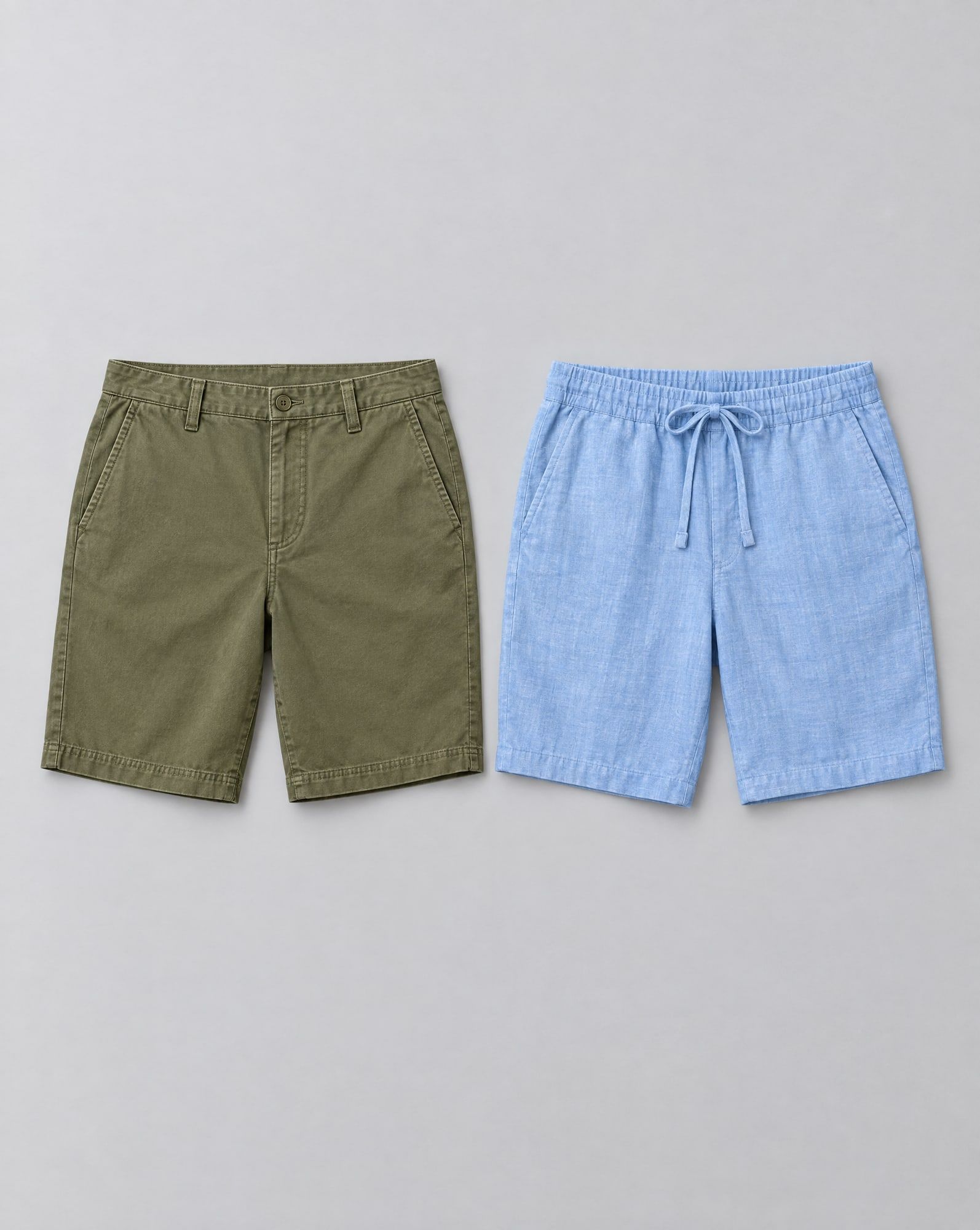 Olive twill bermuda shorts and light blue chambray drawstring shorts laid side by side